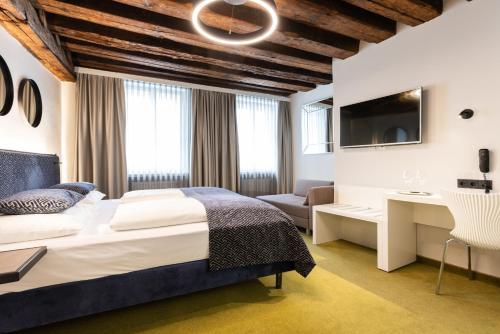Schlafzimmer mit einem Bett, einem Schreibtisch und einem TV in der Unterkunft Boutiquehotel am Dom in Salzburg