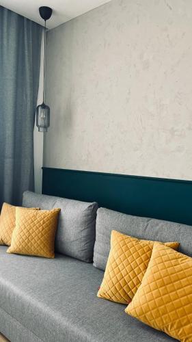 a gray couch with yellow pillows in a room at BOOGIE Home Kamienica Łódzka in Łódź