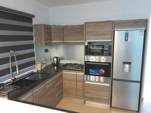 a kitchen with stainless steel appliances and wooden cabinets at J&J in Centre de Flacq