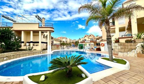 - une piscine avec un palmier à côté d'un bâtiment dans l'établissement Light and cosy apartment in 100 meters from the beach Costa Adeje, à Adeje