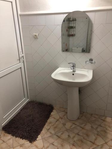 a white bathroom with a sink and a mirror at Kutaisi City Heart Apartment in Kutaisi