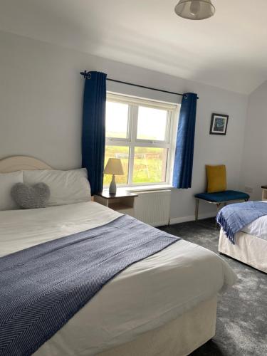a bedroom with a bed and a window with blue curtains at Suantrai Accommodation in Doolin