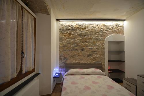 1 dormitorio con cama y pared de piedra en VICO DURAZZO APARTMENT, en Génova