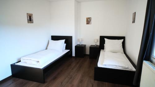 two beds in a room with wooden floors at Mivano-Apartments WiFi Küche NETFLIX in Celle
