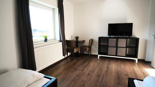 a bedroom with a television and a room with a window at Mivano-Apartments WiFi Küche NETFLIX in Celle