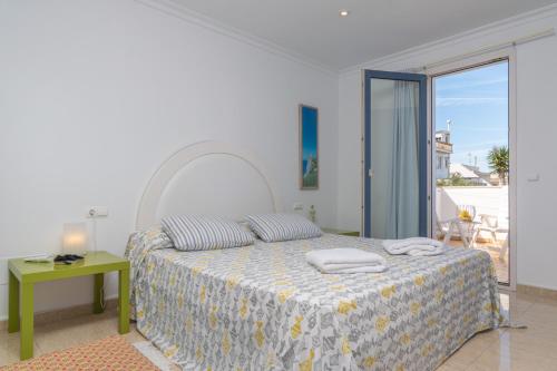 a white bedroom with a bed and a balcony at Casa Acogedora in Portocolom