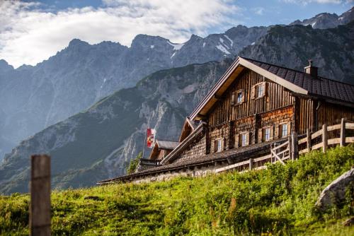 a wooden house on a hill with mountains in the background at AlpenParks Hotel & Apartment Hochkönig in Mühlbach am Hochkönig