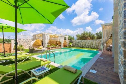 basen z zielonymi parasolami i basenem w obiekcie Villa Green Mare w mieście Prínos