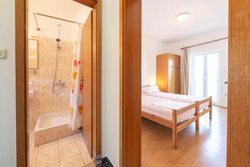 1 dormitorio con 1 cama, ducha y bañera en Apartmani Ivušić en Dubrava