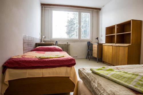 a bedroom with two beds and a desk and a window at Apartments Kolej Vltava in Prague