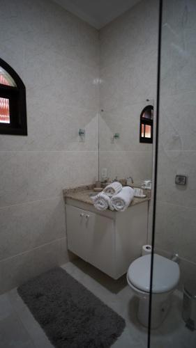 a bathroom with a toilet and a glass shower at Pousada Boutique Mercedes in Extrema