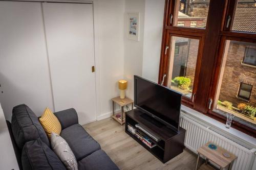a living room with a couch and a flat screen tv at Modern bright studio apartment in south Glasgow in Glasgow