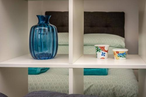 un jarrón azul sentado en un estante con dos tazas en Modern bright studio apartment in south Glasgow, en Glasgow