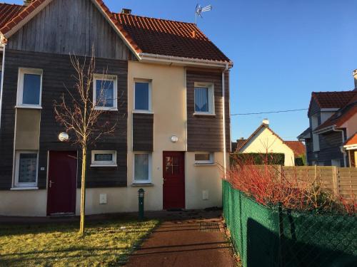une maison avec une porte rouge et une clôture dans l'établissement Maison Familiale entre Plage et Baie d'Authie, Jardin Sud, Parking Privé, 2 Chambres - FR-1-482-33, à Fort-Mahon-Plage
