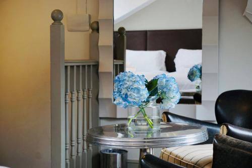 a vase of blue flowers on a table in a room at The Tophams Hotel in London