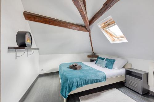Habitación pequeña con cama y reloj en La Nuit du Drouais - T2 en plein cœur de Ville !, en Dreux