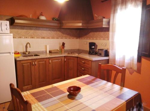 una cucina con un tavolo e un frigorifero bianco di Casa Rural El Olivo a Guijo de Granadilla