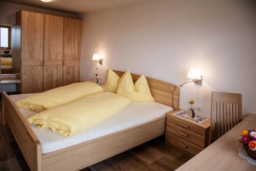 um quarto com uma cama com lençóis brancos e almofadas amarelas em Forchnerhof Apt Ploseblick em Maranza