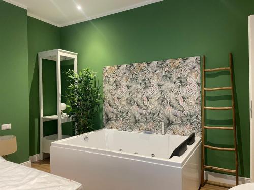 a bathroom with a bath tub and a green wall at COMÓ EXCLUSIVE in Aprilia