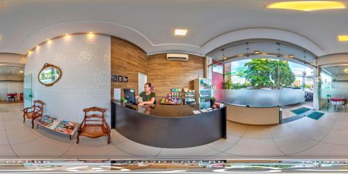 a lobby of a store with a man sitting at a counter at Suites Residence in Recife