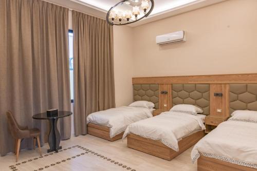 1 dormitorio con 2 camas, mesa y silla en Adam's Luxury Villa DeadSea, en Sowayma
