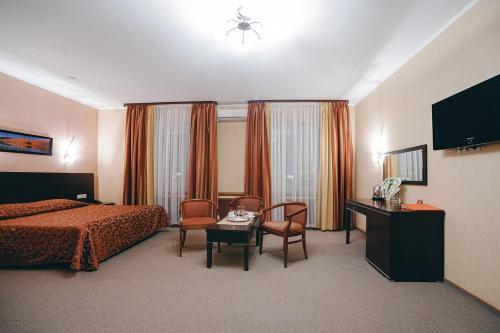 スルグトにあるMetelitsa Hotelのベッド、テーブル、椅子が備わるホテルルームです。
