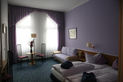 a hotel room with two beds and a couch at Hotel Am St. Georg in Leipzig