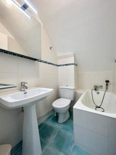 une salle de bain blanche avec un lavabo et des toilettes dans l'établissement Bel appartement proche du port de Sainte Marine, à Combrit
