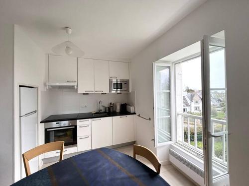 une cuisine avec des placards blancs et une grande fenêtre dans l'établissement Bel appartement proche du port de Sainte Marine, à Combrit