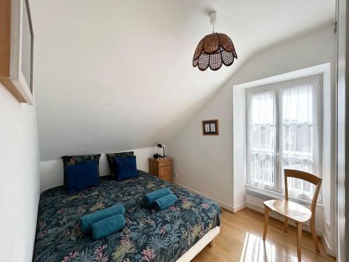 - une chambre avec un lit doté d'oreillers bleus et d'une chaise dans l'établissement Bel appartement proche du port de Sainte Marine, à Combrit