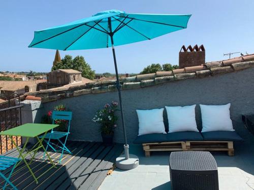 a blue couch and an umbrella on a patio at AGDE HOLIDAYS in Agde