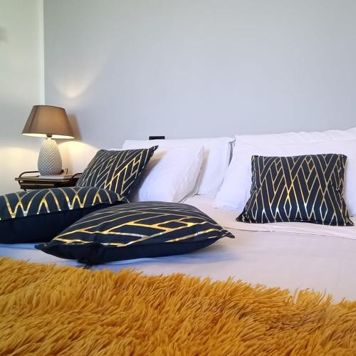 1 cama con almohadas blancas y negras y lámpara en ArtGallery Apartment - Villa immersa nel verde - Deluxe, en Viterbo