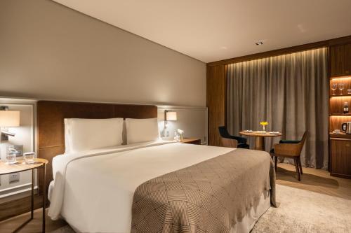 a hotel room with a large bed and a table at L'Hotel PortoBay São Paulo in Sao Paulo