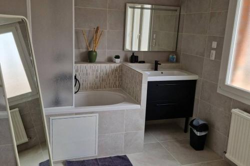 ein Badezimmer mit einer Badewanne, einem Waschbecken und einem Spiegel in der Unterkunft Maison familiale in Dunkerque