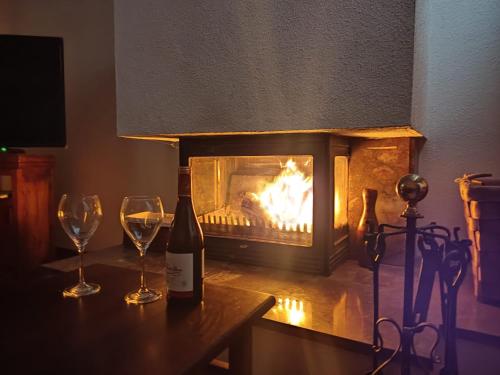 a bottle of wine and two glasses on a table with a fireplace at La casa de la Plaza - WIFI - Barbacoa - Chimenea in Cirueña