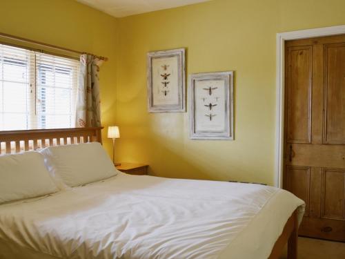 a bedroom with a white bed and a window at High Moor Cottage in Dufton