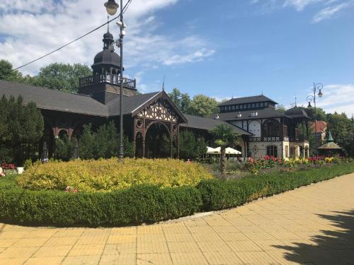 a large building with a clock tower in a garden at Olivia apartament przy deptaku in Szczawno-Zdrój