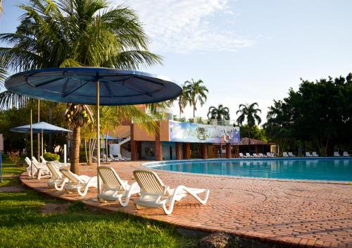 a row of chairs and an umbrella next to a swimming pool at Hotel Terramia Resort in Santa Cruz de la Sierra