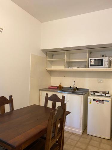 a kitchen with a wooden table and a white refrigerator at Apart Bosch House in Vicente López