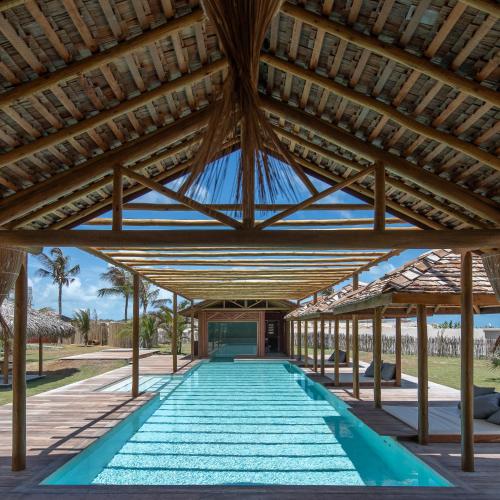 an open pavilion with a pool under a wooden roof at Jaguaríndia Village in Fortim