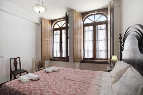 a bedroom with a large bed with two windows at Silver coast villa in Alcobaça