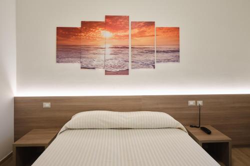 una camera da letto con un letto con quattro dipinti sul muro di HOTELRISTORANTE IL PUNTO a Marotta