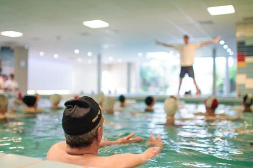 un homme dans une piscine regardant un homme jouer au frisbee dans l'établissement Thermotel, à Dax