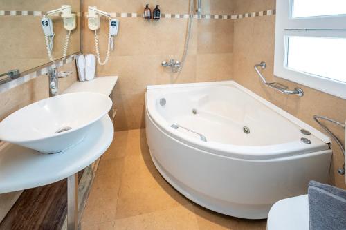 a bathroom with a large tub and a sink at Smy Santorini Suites & Villas in Pirgos