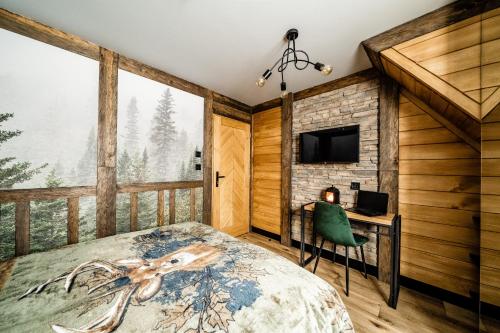 a bedroom with a bed and a desk and a tv at Brzozowa Osada - Premium Chalets Zakopane in Zakopane