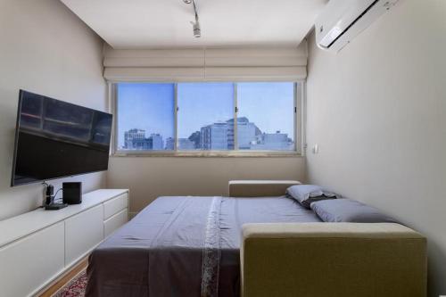 um quarto com uma cama e uma grande janela em Flat em Copacabana no Rio de Janeiro