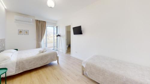 a hotel room with two beds and a flat screen tv at Accòmodati - Camere e Appartamenti in Marina di Gioiosa Ionica
