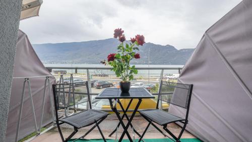 a table with a vase of flowers on a balcony at Hôtel du Poète in Aix-les-Bains