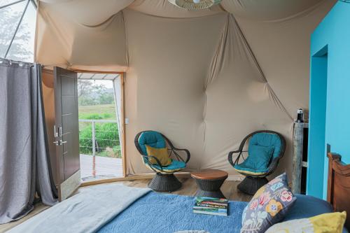 a bedroom with two chairs in a tent at Badu Lodge Puriscal in Santiago