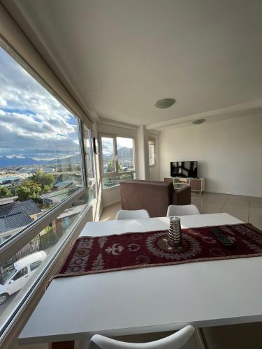 Habitación con mesa, sillas y ventana grande. en Depto en Los Canelos en Ushuaia